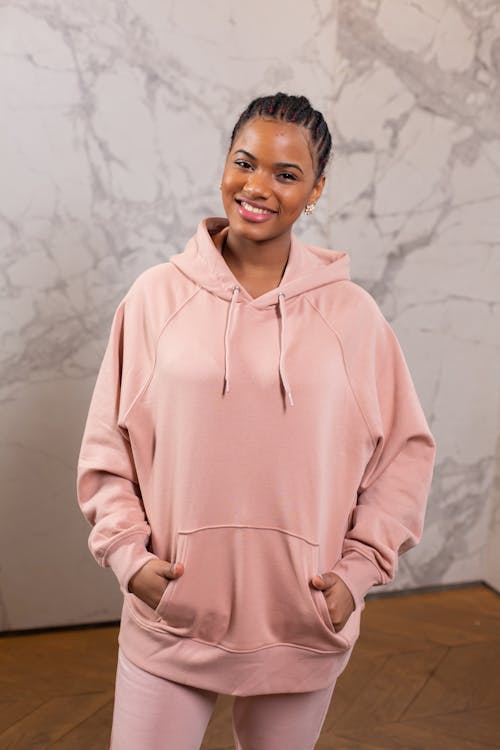 Cheerful black woman with hands in pocket in trendy hoodie