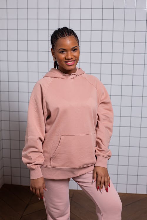 Stylish young cheerful black woman in pink hoodie and trousers