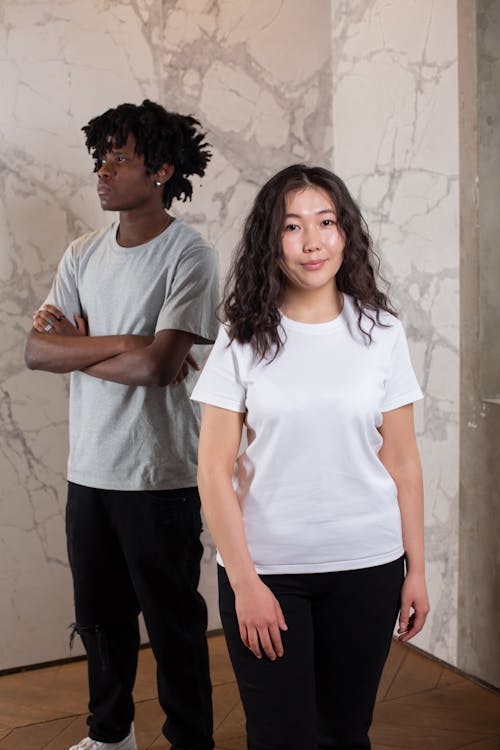 Positive young Asian woman near pensive black man