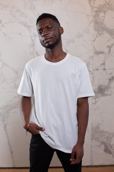 Young confident African American male in simple white shirt looking at camera near wall with abstract patterns