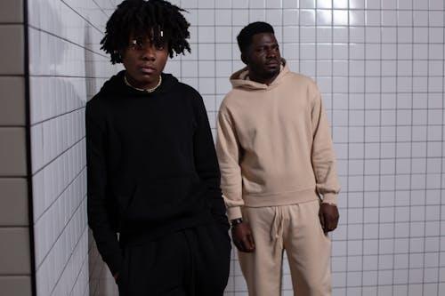 Young African American males in black and beige sportive clothes in front of tiled wall