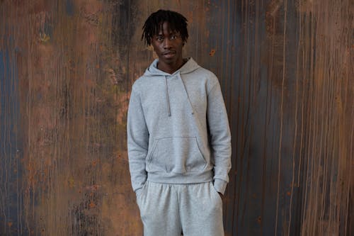 Cool young black man in hoodie standing in studio with hands in pockets