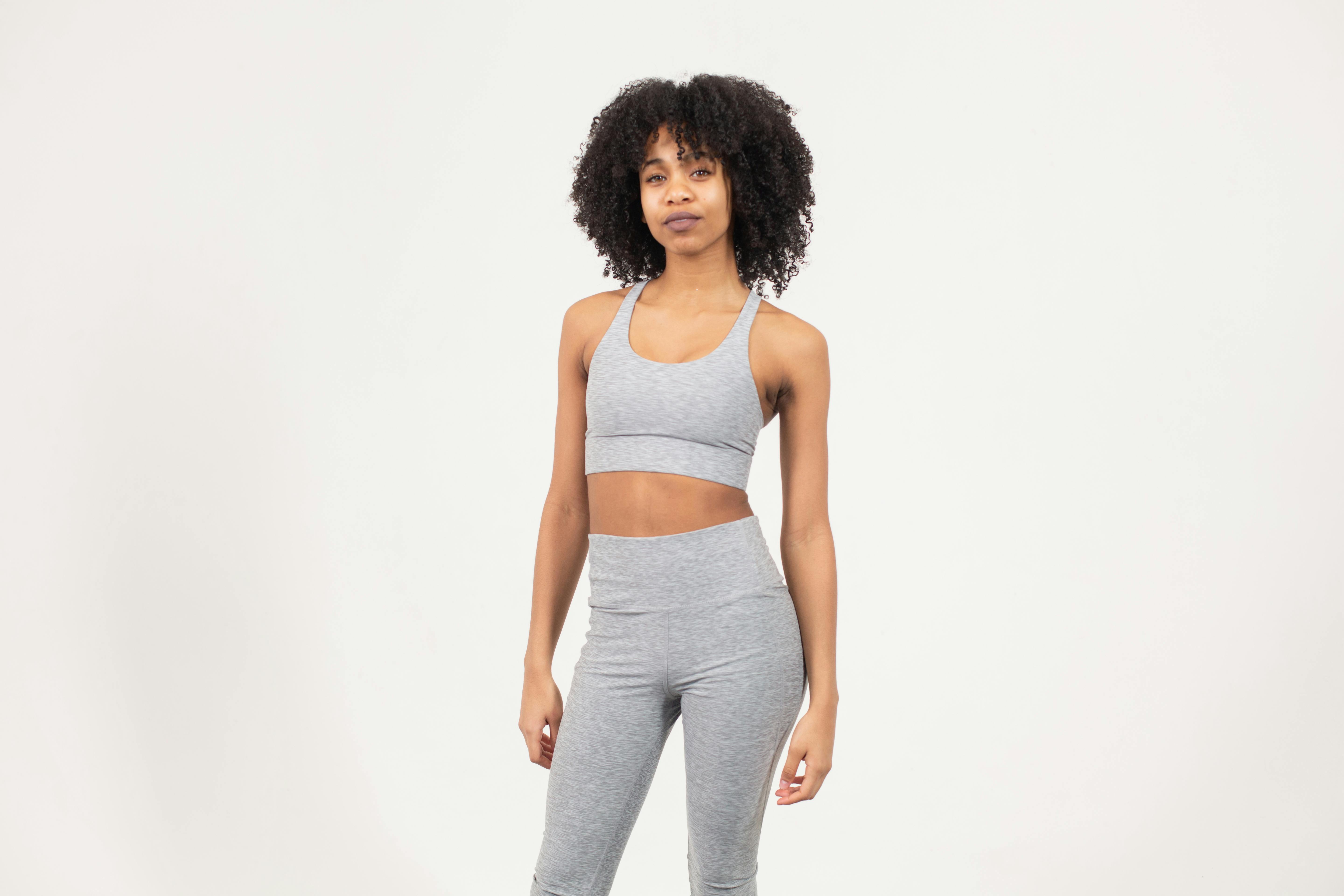 slim young african american lady in activewear standing in white studio