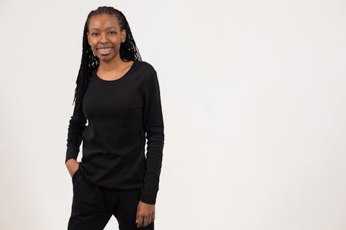 Happy young black woman standing in white studio and smiling at camera