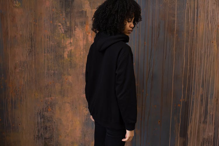 Serious Black Woman In Sports Suit Standing Against Wooden Wall