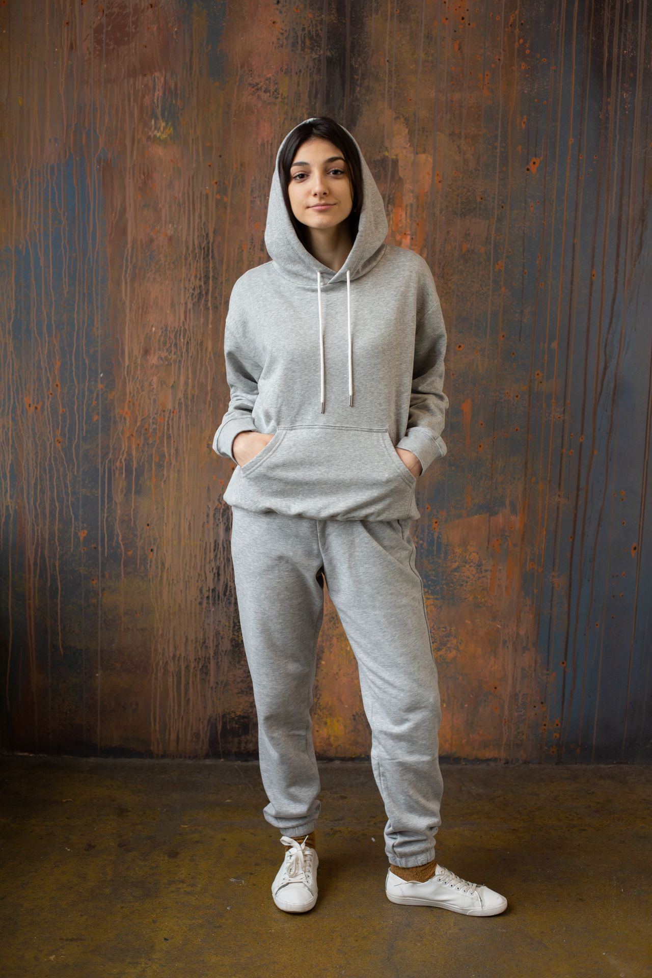 Woman in a gray hoodie and matching sweatpants with white sneakers