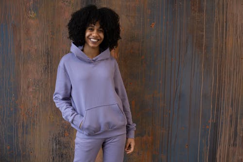 Happy black woman in hoodie standing in studio