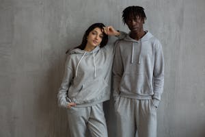 Young multiracial sportspeople wearing gray comfy hoodies and pants standing with hands in pockets and looking at camera
