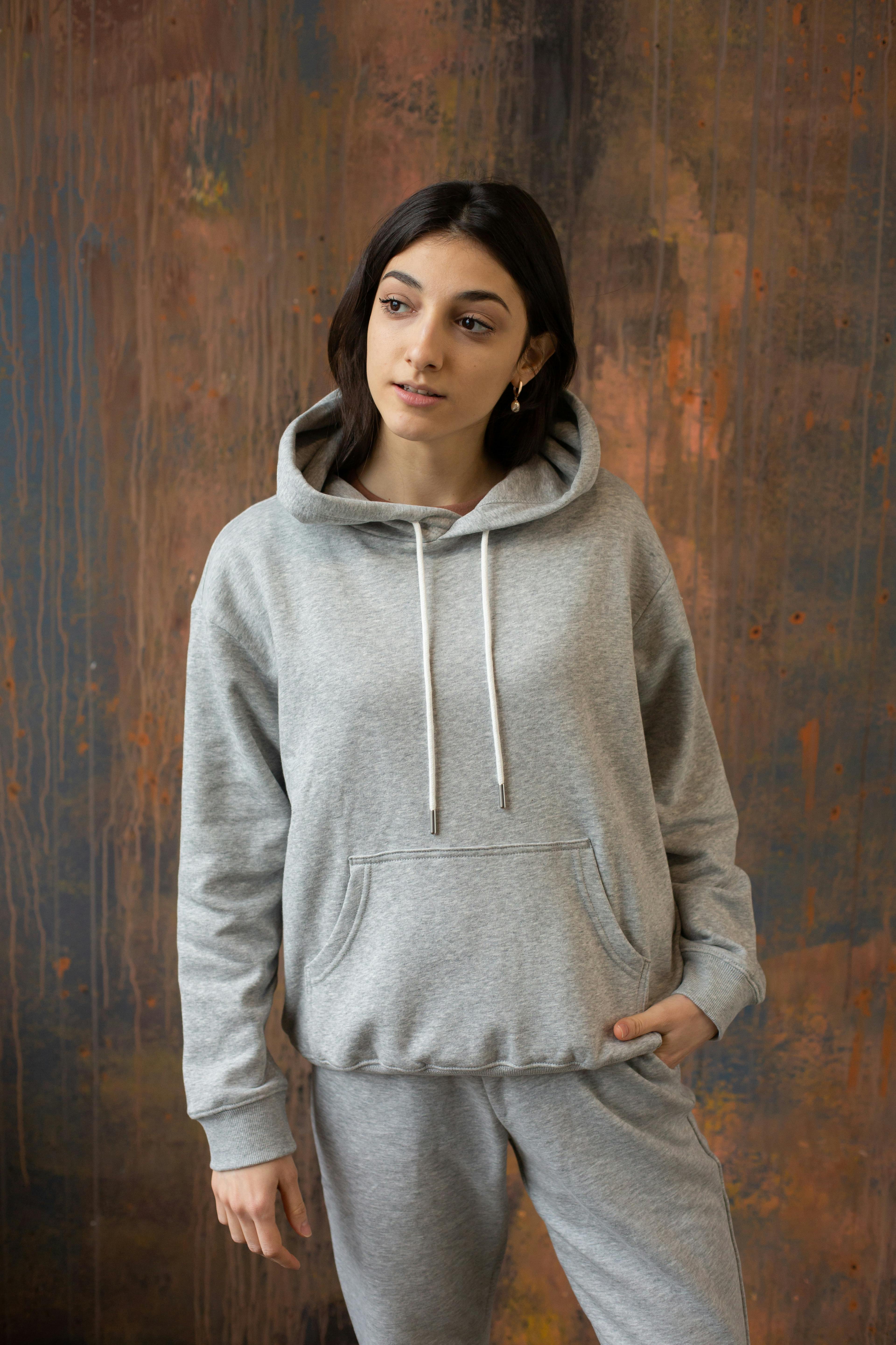 young ethnic woman in gray activewear standing against wooden wall