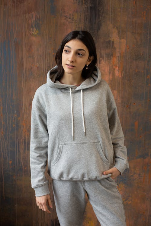 Young ethnic woman in gray activewear standing against wooden wall ...