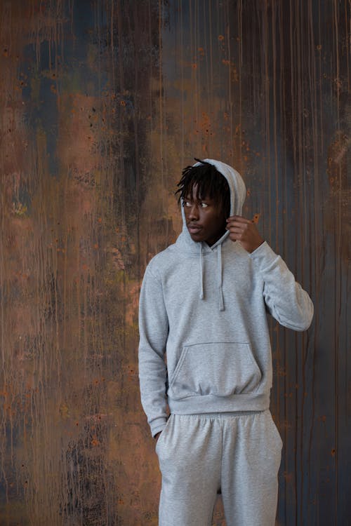 Serious black man in sportswear standing against wooden wall