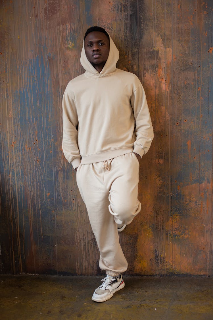 Confident Black Man In Hood Standing Near Wooden Wall