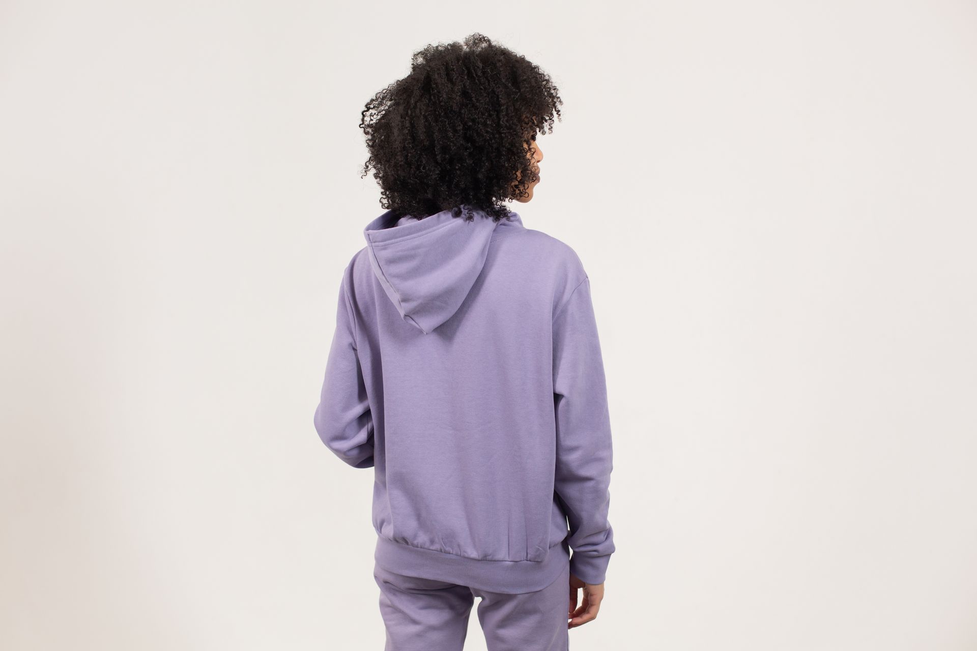 Faceless black woman in violet hoodie standing on white background
