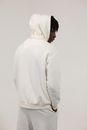 Serious black man in white hooded sportswear against light background