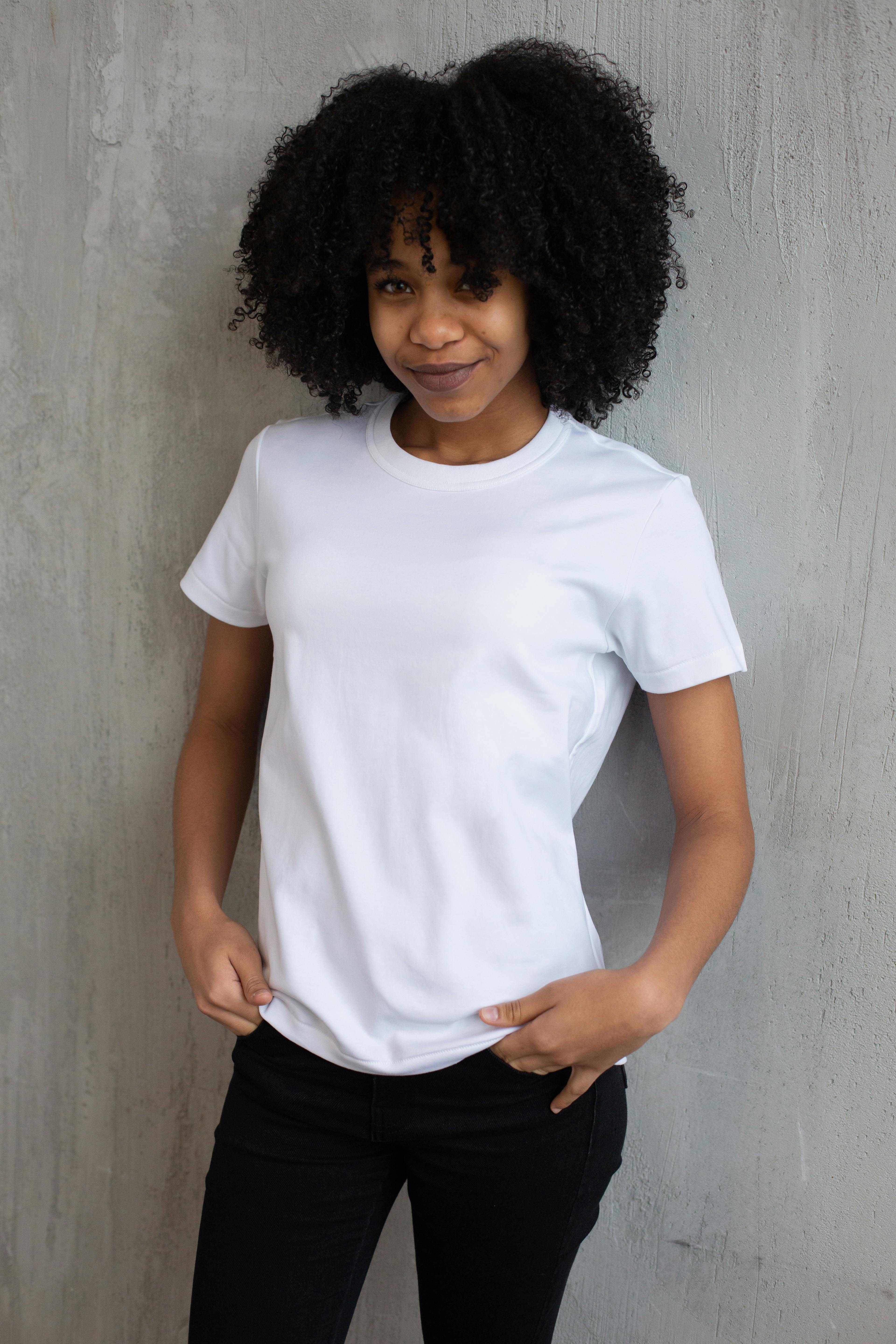 smiling black woman in casual clothes standing against gray wall