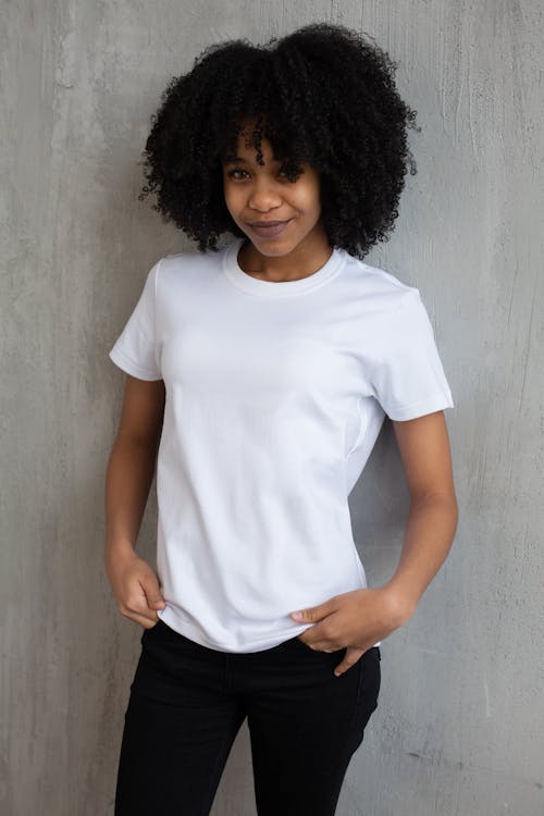 Smiling black woman in casual clothes standing against gray wall