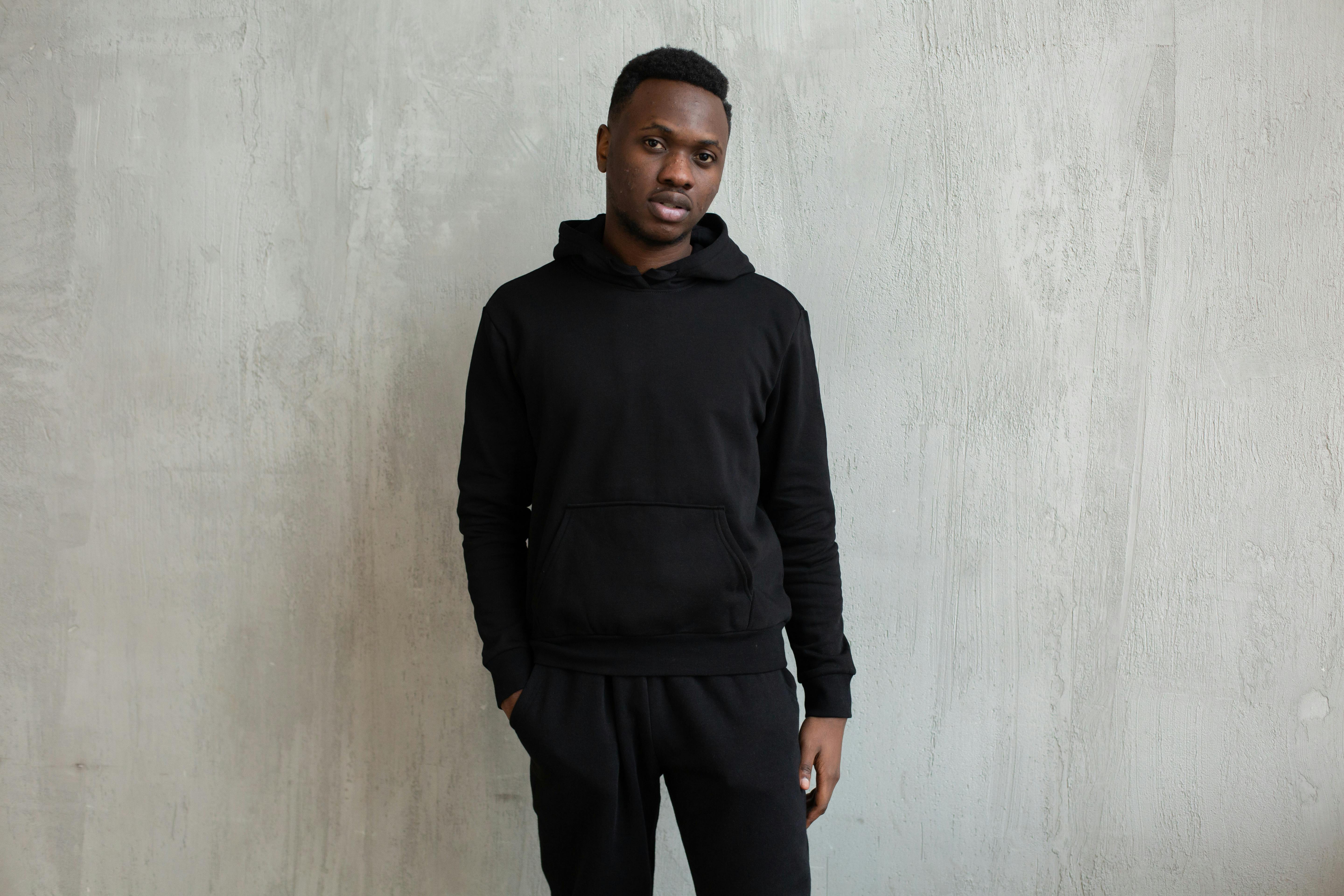 Man in black and white adidas hoodie standing near wall photo