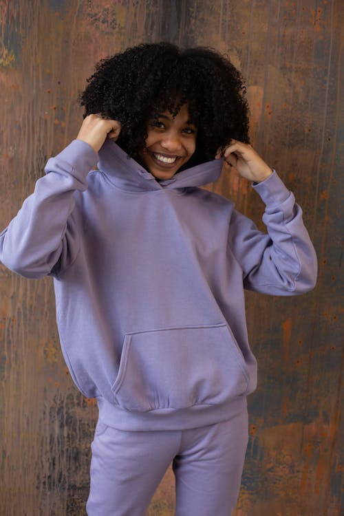 Smiling African American lady wearing hoodie near wall