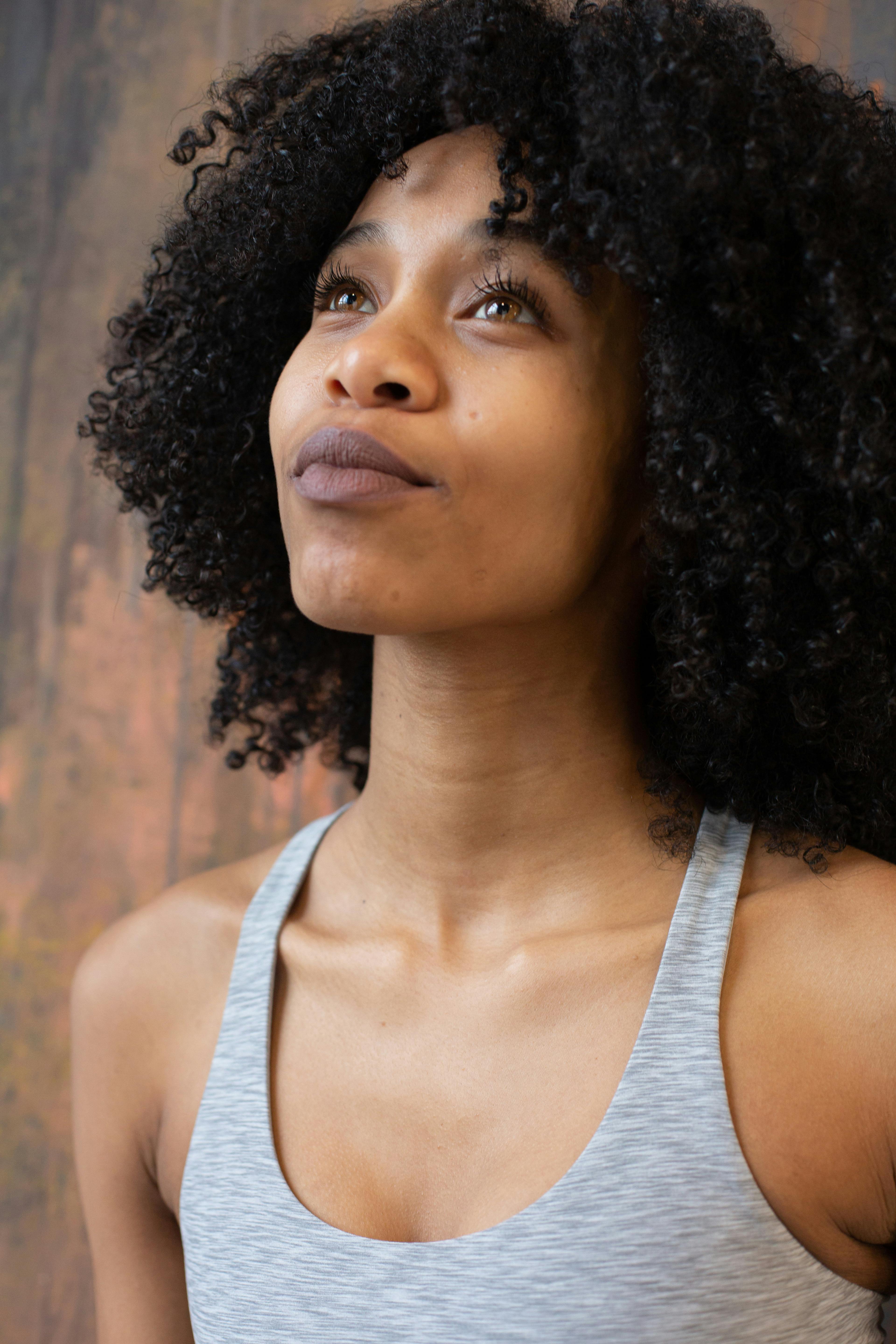 dreamy black woman near wall in light studio