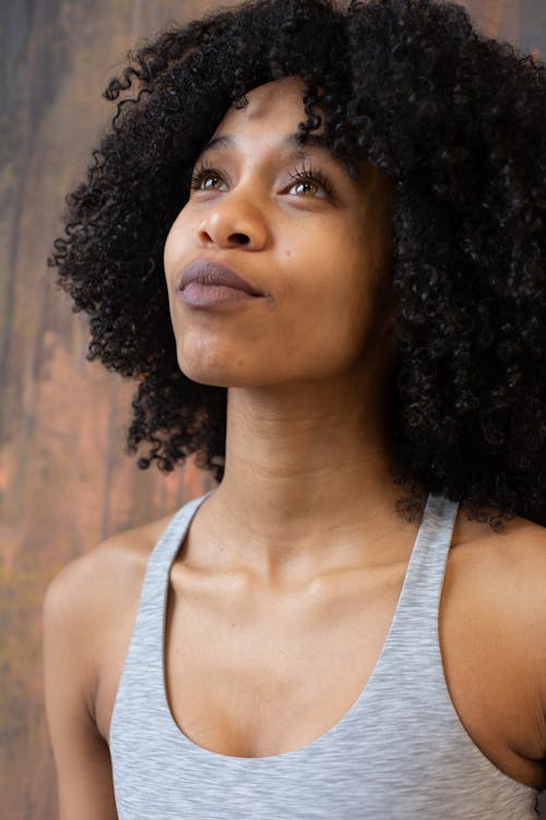 Dreamy black woman near wall in light studio