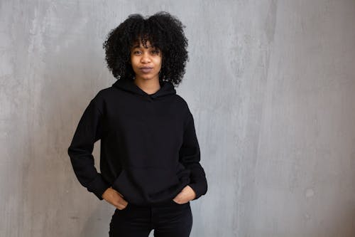 Young African American female model with Afro hairstyle wearing hoodie and jeans looking at camera