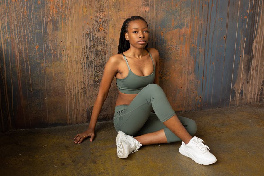Woman wearing a sage active set sitting on a studio floor