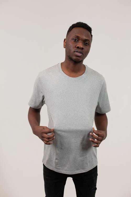 Handsome confident African American man wearing gray t shirt and black trousers on beige background and looking at camera