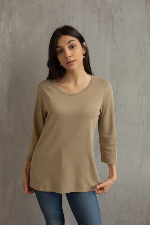 Stylish woman in beige blouse before gray wall