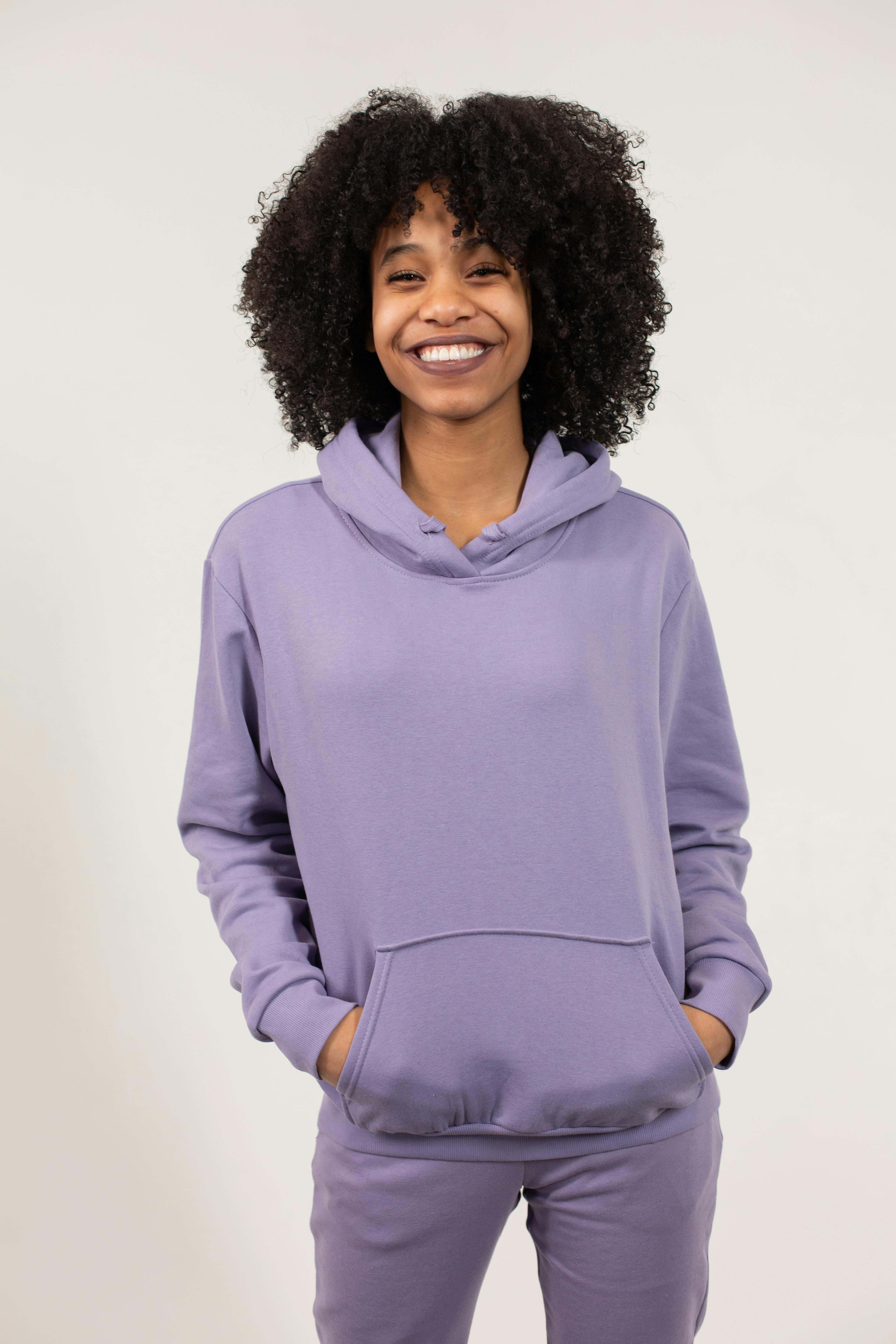 cheerful black woman in violet clothes with hands in pockets