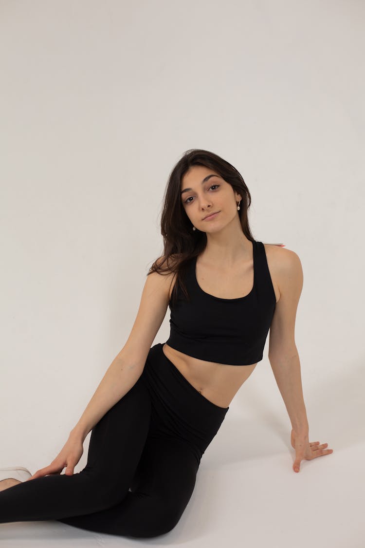 Fit Female In Black Leggings And Top Resting On Floor