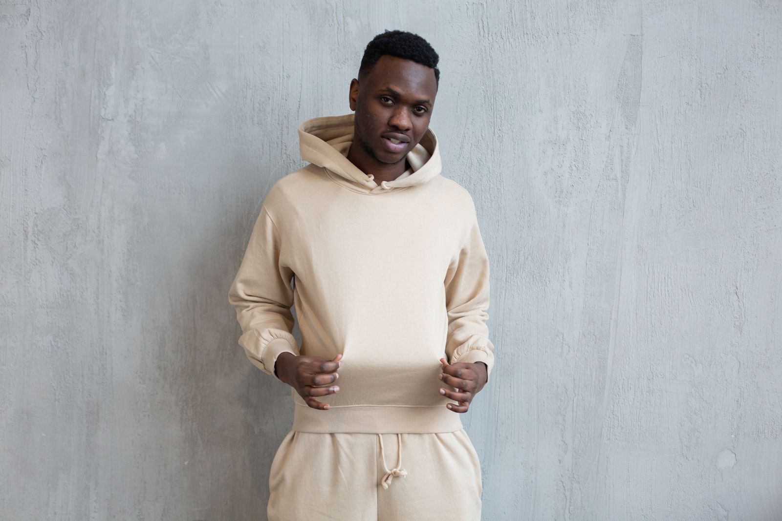 Un jeune homme en tenue streetwear présente son sweat à capuche