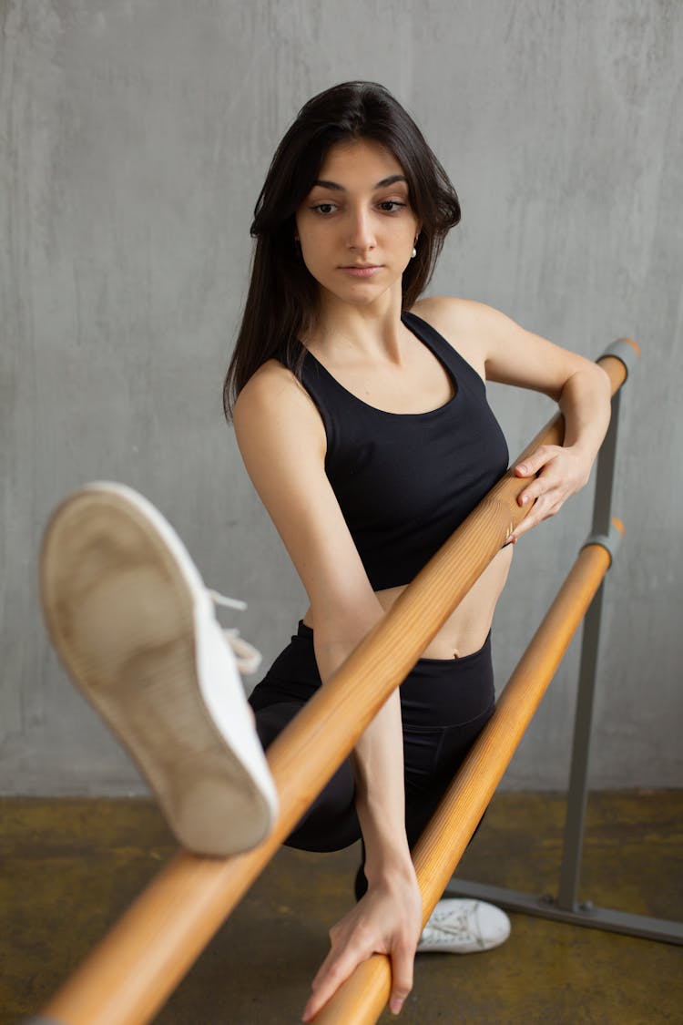 Slim Ethnic Woman Stretching Near Barre