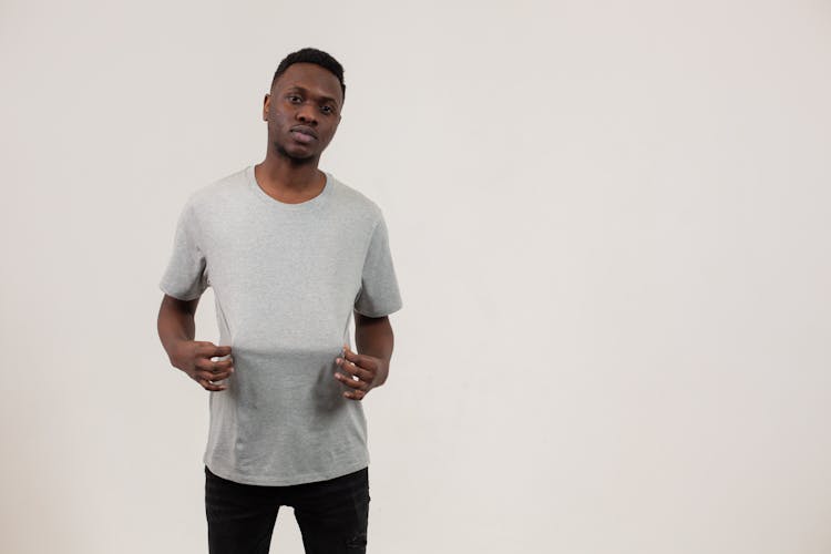 Black Man Holding T Shirt Standing Against White Background