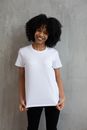 Charming African American female in white t shirt and tight pants smiling widely and looking at camera