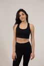Fit female model wearing sports bra and leggings revealing bare tummy standing on white background and looking away