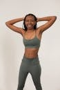 Positive African American female athlete in activewear keeping hands on head and smiling while looking at camera