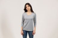 Charming young female with dark straight hair and brown eyes in trendy outfit looking at camera while standing on gray background in studio