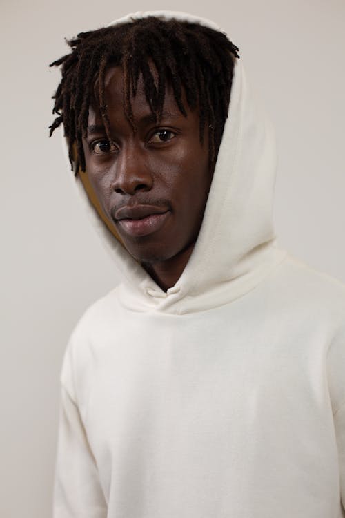 Black man in hoodie near white wall