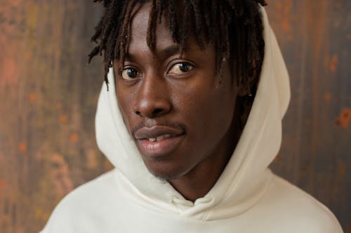 Young African American male with dreadlocks in trendy white hoodie with hood on head