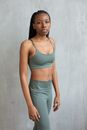 Slim woman in sportswear standing near wall