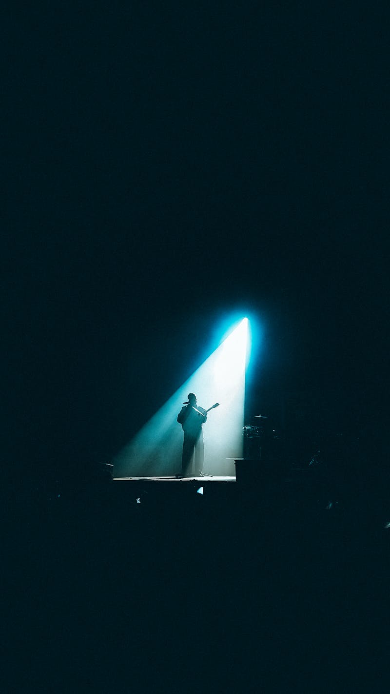 Guitarist performing solo under dramatic stage lighting