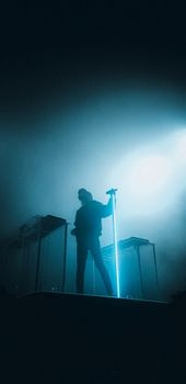 A musician stands silhouetted on stage with dramatic lighting, creating a captivating scene.