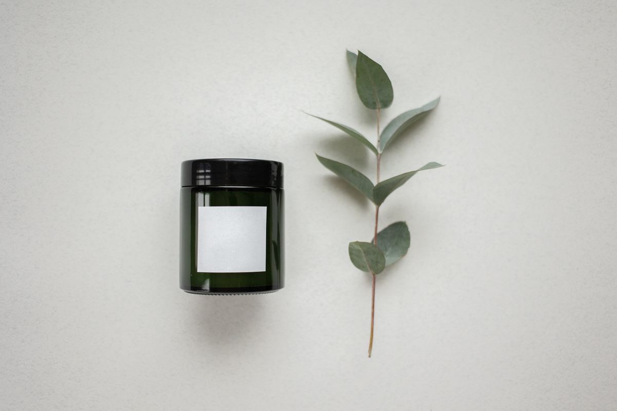 Branded glass jar next to a eucalyptus stem