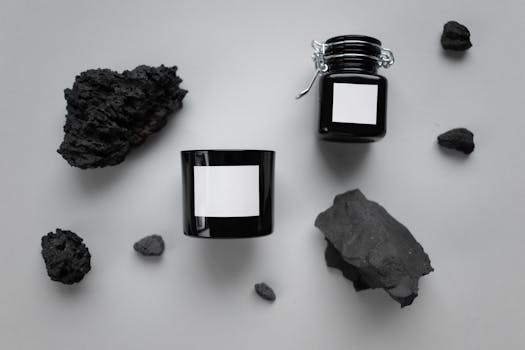 Elegantly arranged charcoal skincare products and coal rocks on a gray surface, conveying a natural theme.