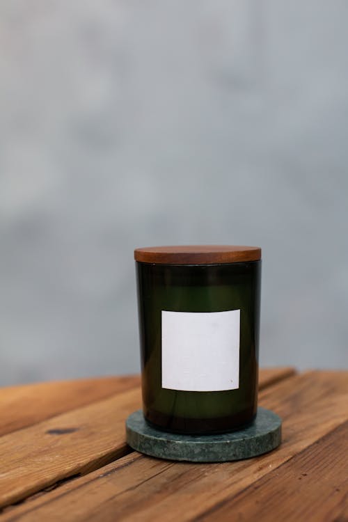 Green Glass Candle Jar on Wooden Surface · Free Stock Photo