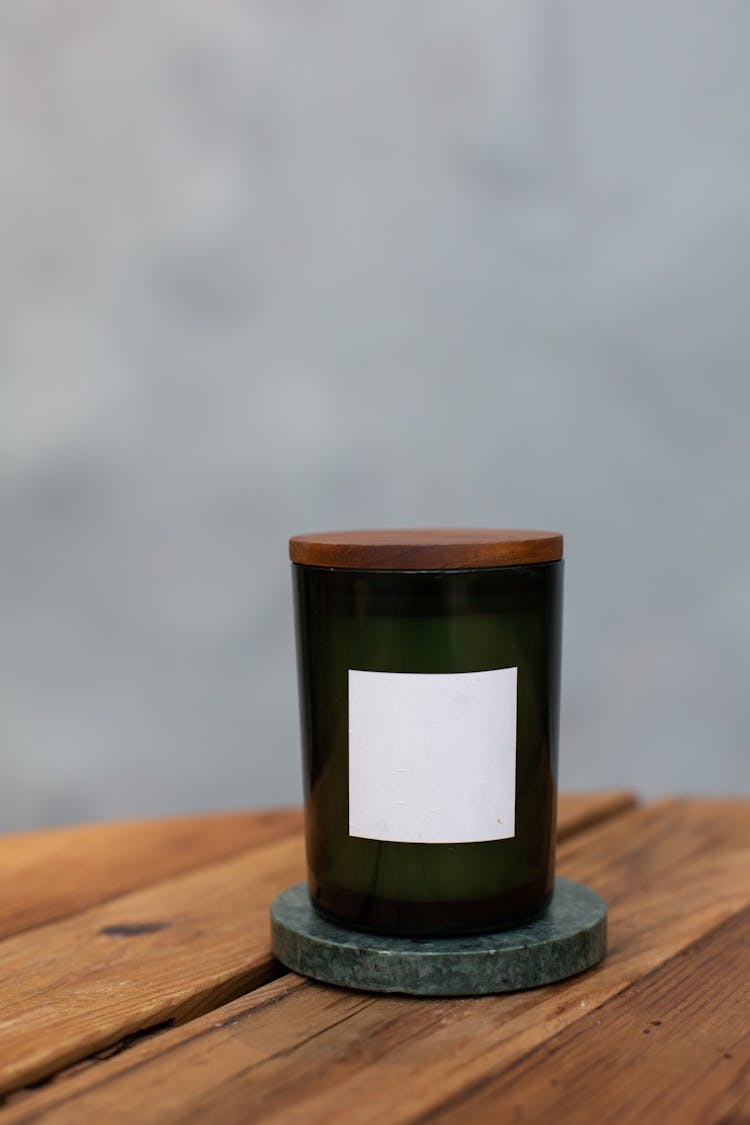 Green Glass Candle Jar On Wooden Surface