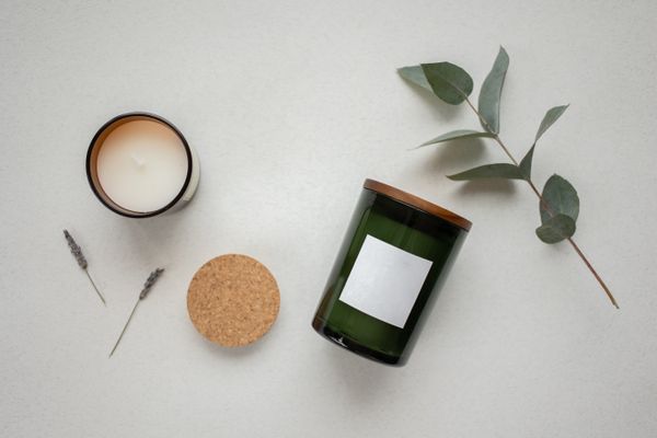 Green glass candle with a cork lid and eucalyptus sprig — KATRIN BOLOVTSOVA on Pexels
