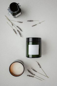 Top view of green jars with candles and lavender on a white surface, perfect for aromatherapy branding.