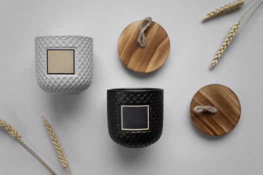 Minimalist flat lay of textured ceramic containers and wooden lids on white surface.