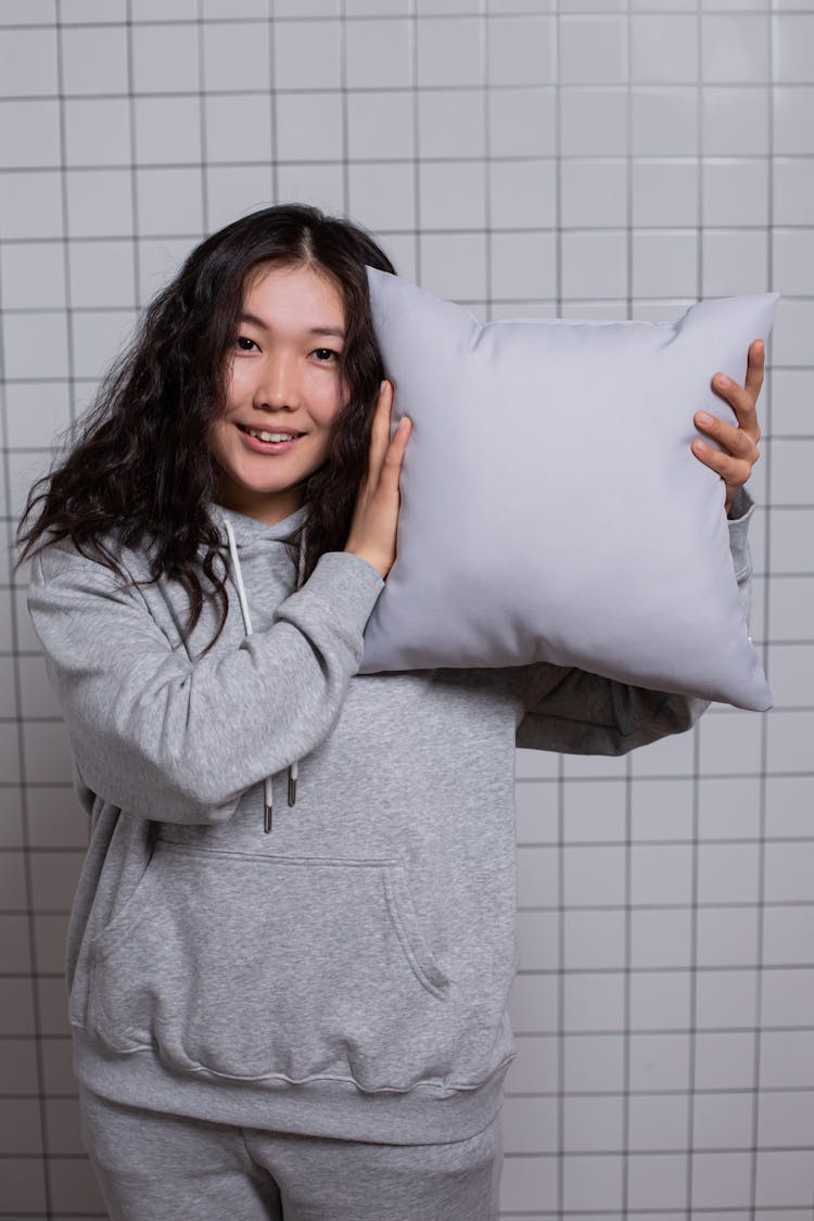 A Woman In Gray Hoodie Holding A Pillow